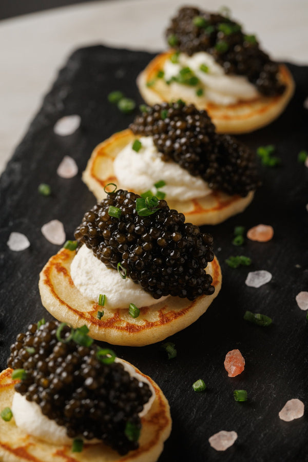 Classic caviar service - Attilus caviar on golden blinis with creme fraiche and chives
