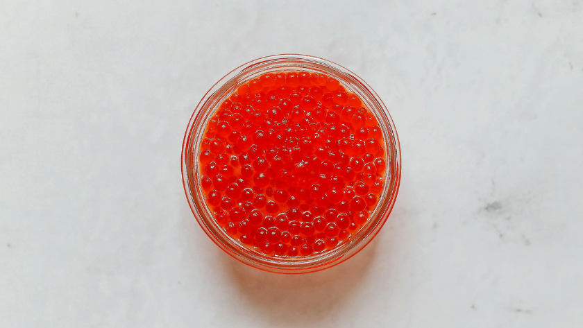 A small glass bowl filled with bright orange salmon roe pearls